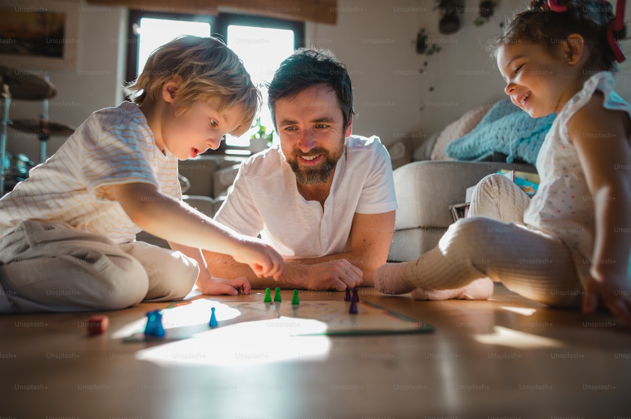 Pai com dois filhos pequenos jogando um jogo de tabuleiro em casa